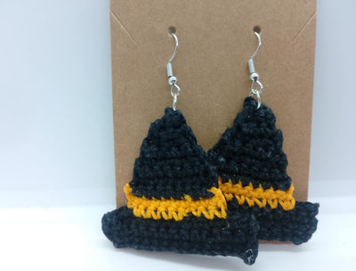 The Handmade Crochet Halloween Earrings by FashionableCrochet add a touch of spooky charm with their black witch hat design and orange bands. These earrings come with silver hooks for wearing and are displayed against a brown cardboard backing.