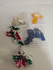 A variety of crochet keychains, featuring designs like a butterfly, candy cane, and the Handmade Crochet Cross Keychain – Spiritual Amigurumi Accessory by FashionableCrochet, are displayed on a table. Each piece is meticulously handcrafted and individually packaged.